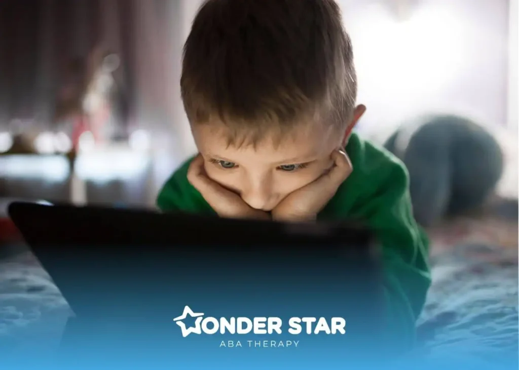 An autistic boy on bed watching a tablet with intense focus, illustrating screen engagement and attention in young children.
