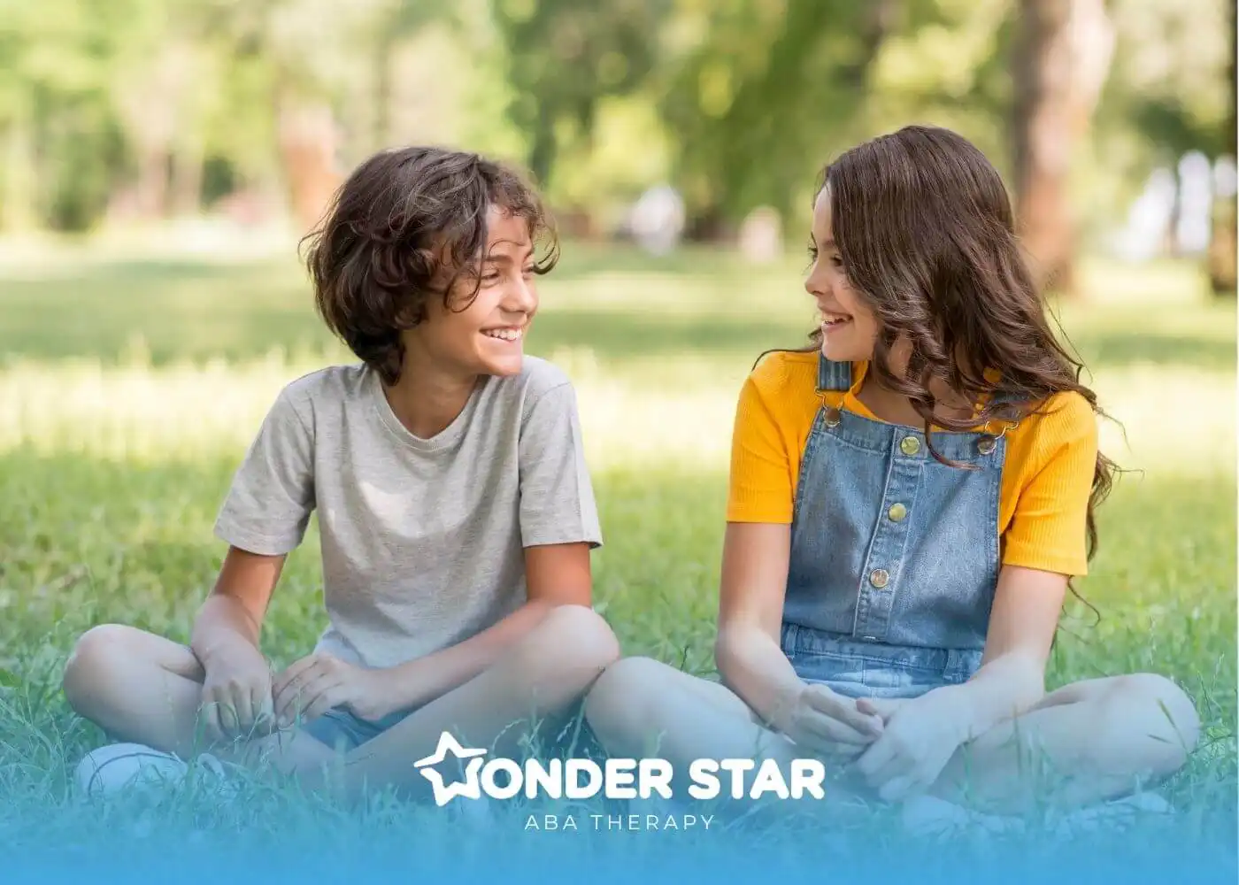 Two autistic children sitting on grass in a park, smiling at each other and sharing a friendly, relaxed moment outdoors.