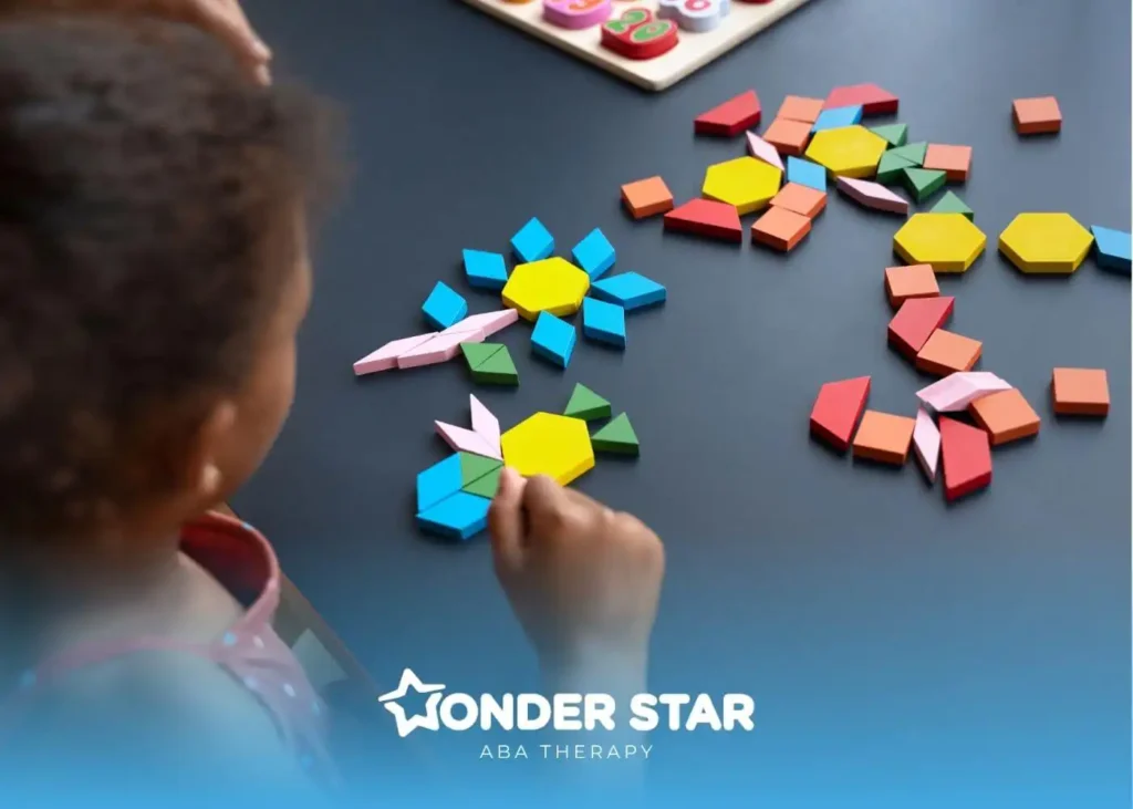 Autistic young child arranging bright geometric pattern blocks on a table, building flower shapes during learning activity.