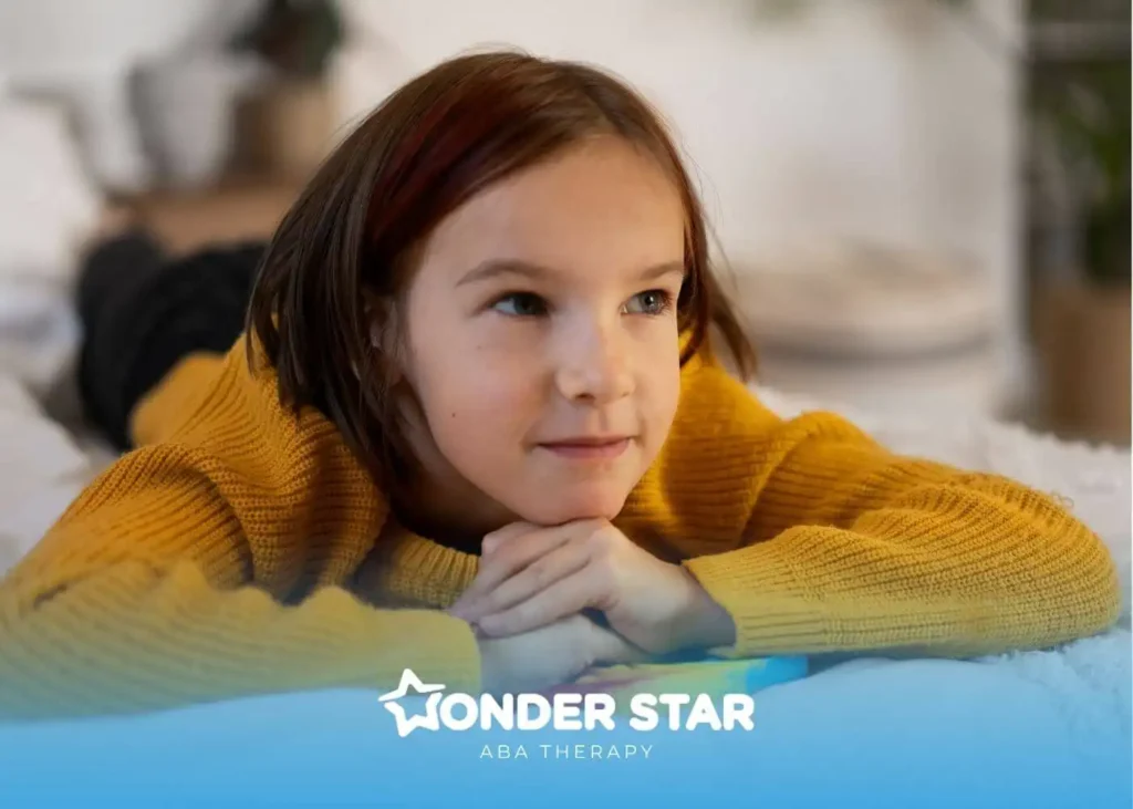An autistic girl in yellow sweater resting on a bed, thoughtful expression reflecting developmental observation context.