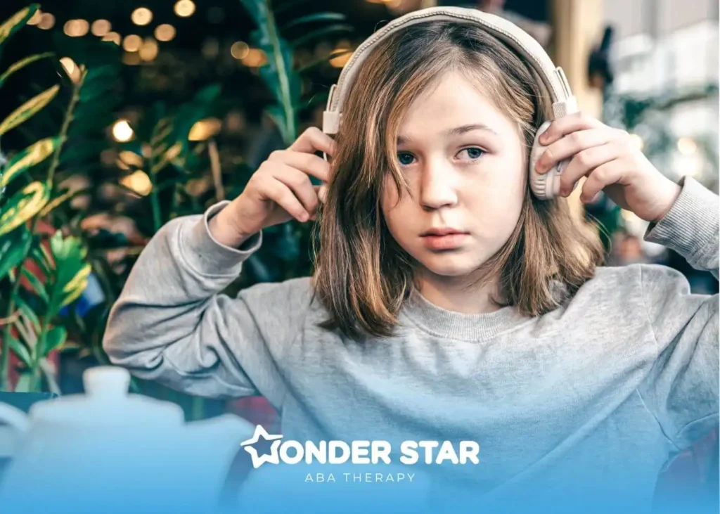 Autistic child wearing large headphones indoors, adjusting them to reduce noise in a busy café environment.