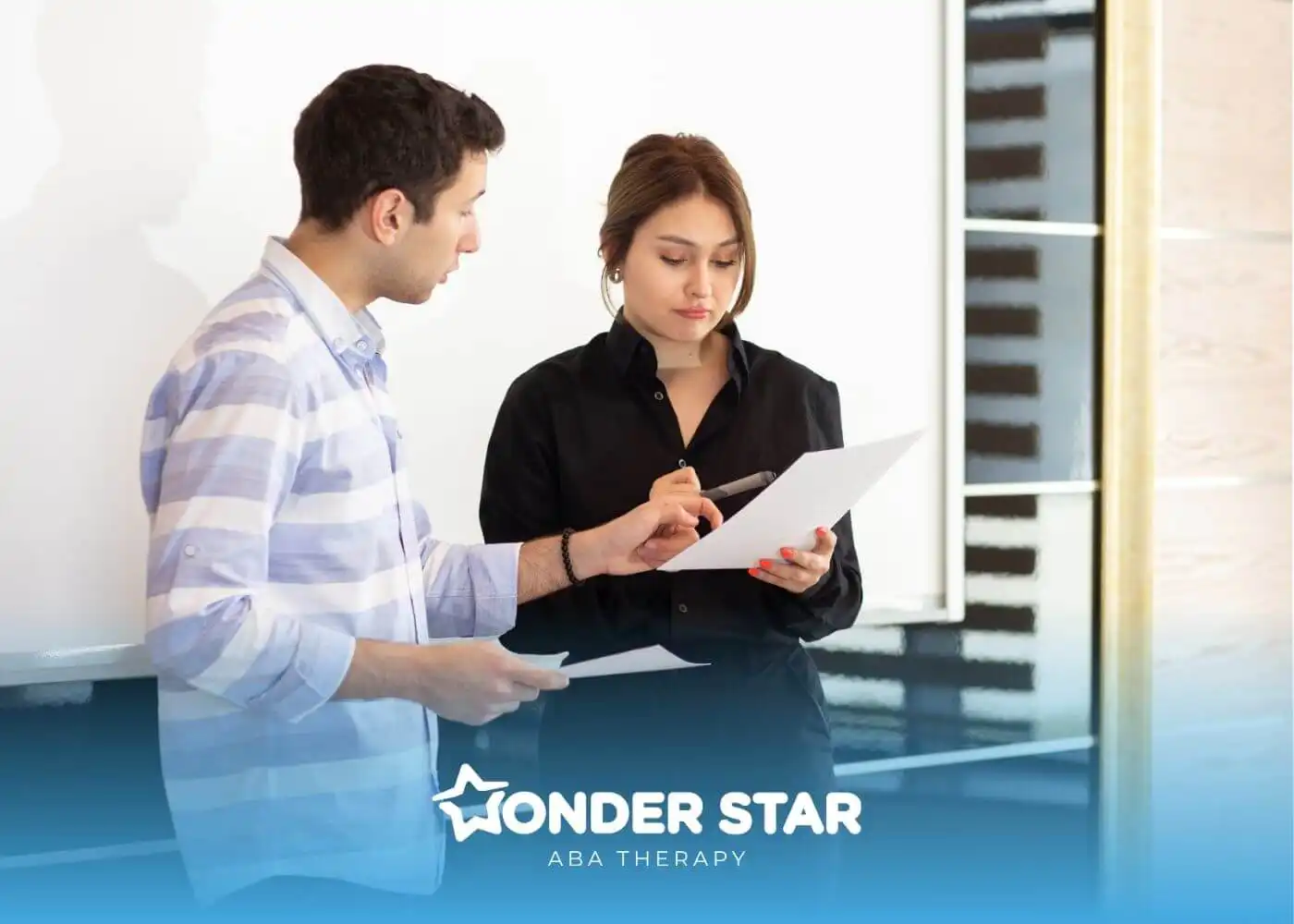 Two therapist reviewing paperwork together, discussing RBT supervision requirements and ABA compliance standards.
