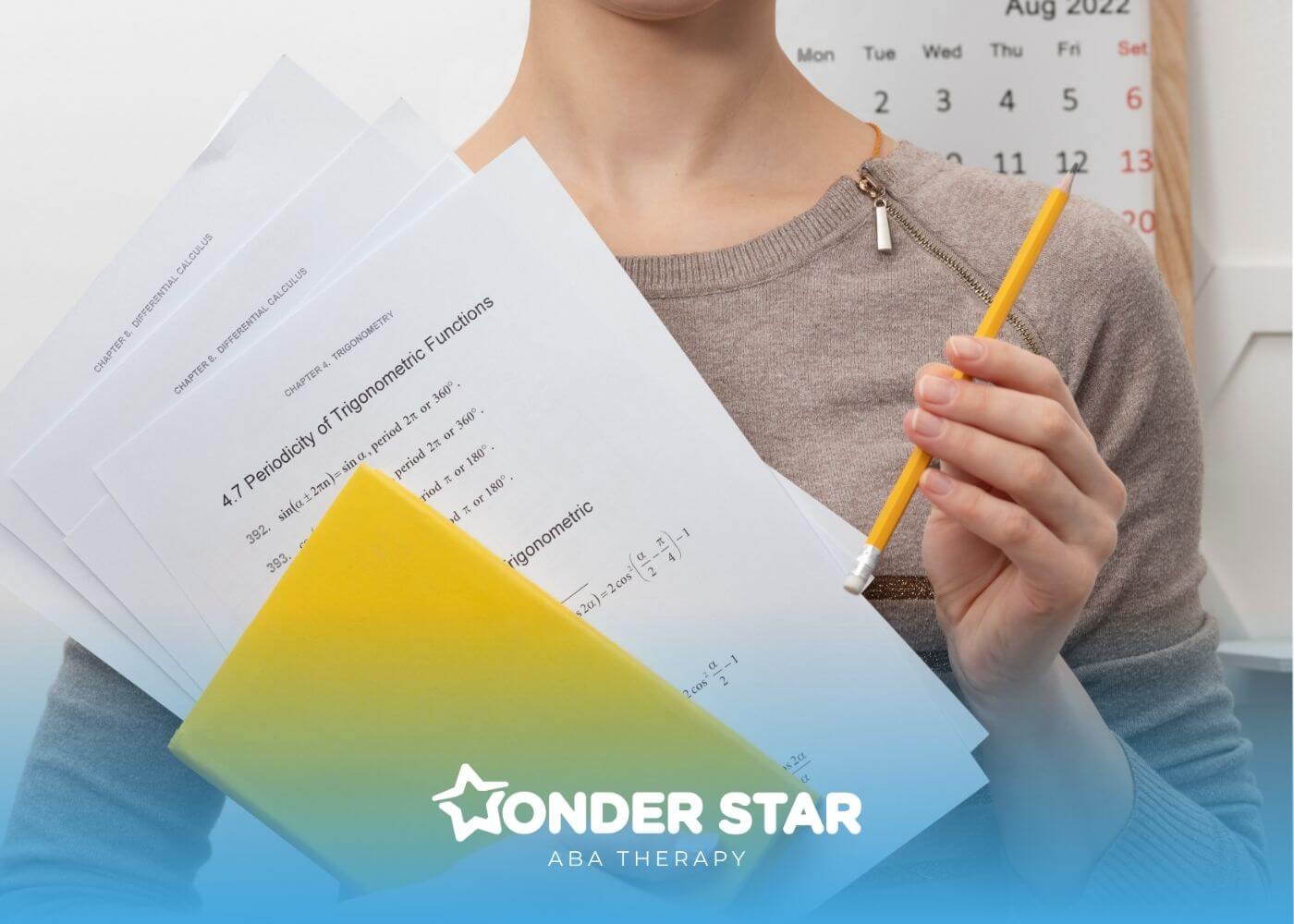 ABA student holding trigonometry worksheets, a yellow notebook, and pencil while preparing for math study or exam practice.