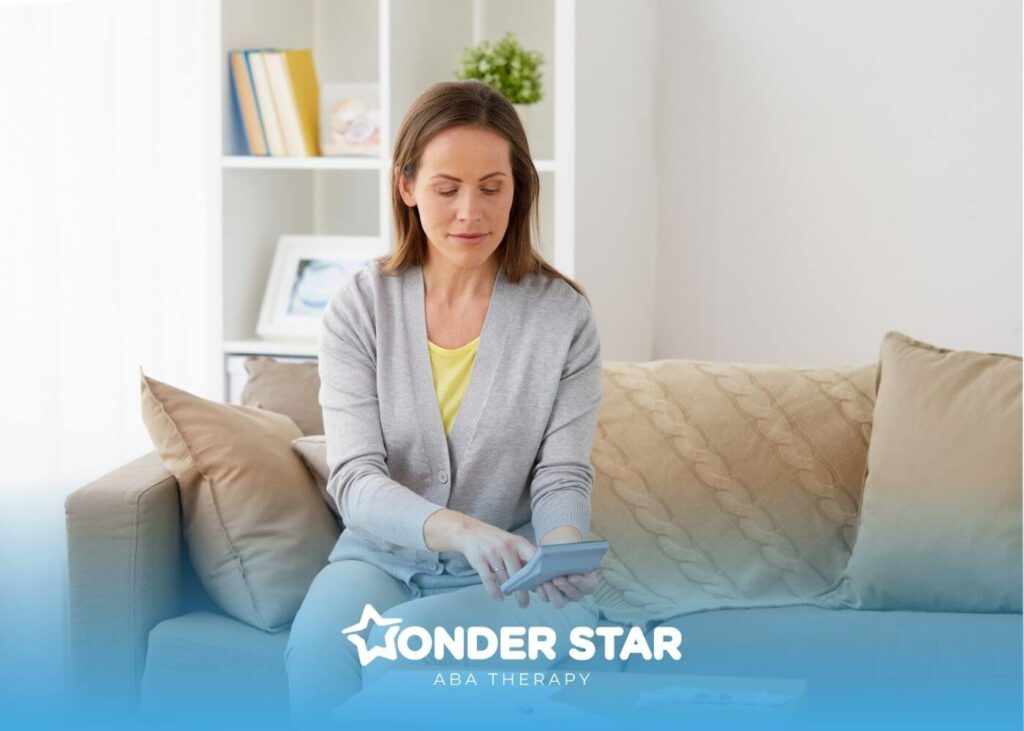 ABA woman sitting on a couch using a calculator and reviewing bills and cash while managing household finances.
