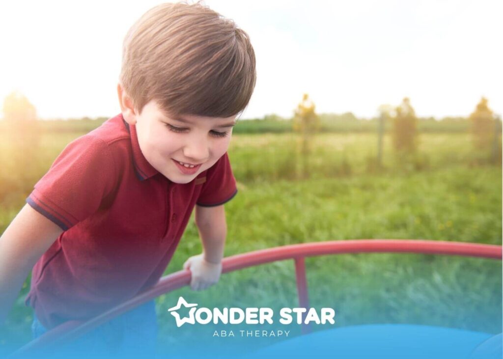Autistic boy smiling while playing on playground equipment outdoors, representing early childhood development.