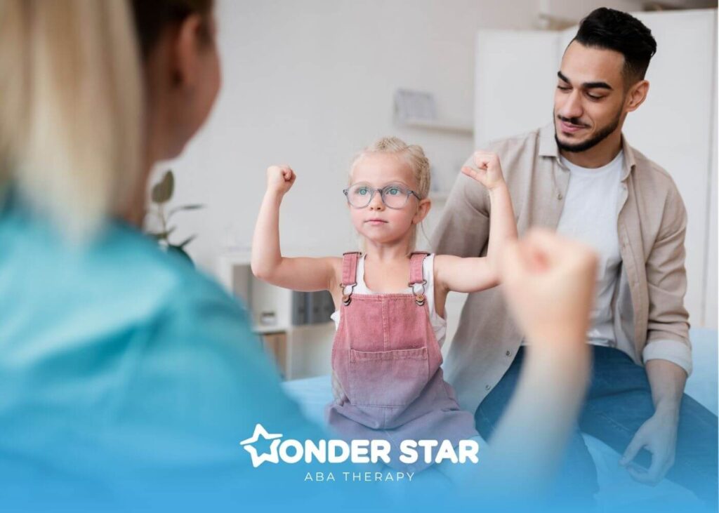 Autistic girl raising both arms confidently while sitting with a parent & therapist during a supportive ABA therapy session.
